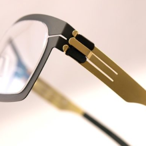 A close up on the hinge on a pair of glasses in black and gold