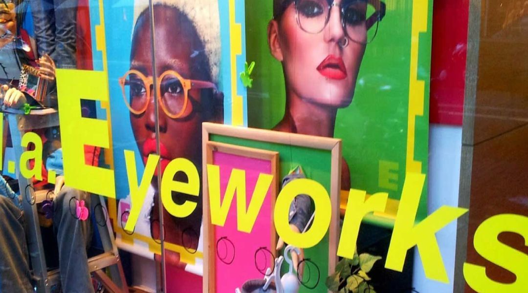 Colorful window display of different faces wearring eyewear at an l.a.Eyewroks store