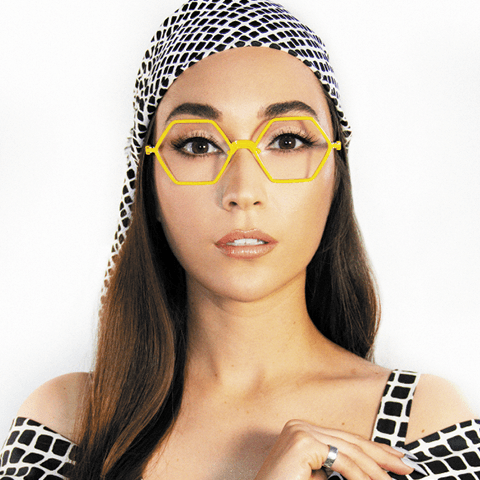 Woman in a black and white patterned outfit wearing a pair of yellow octagon-shaped la Eyeworks frames