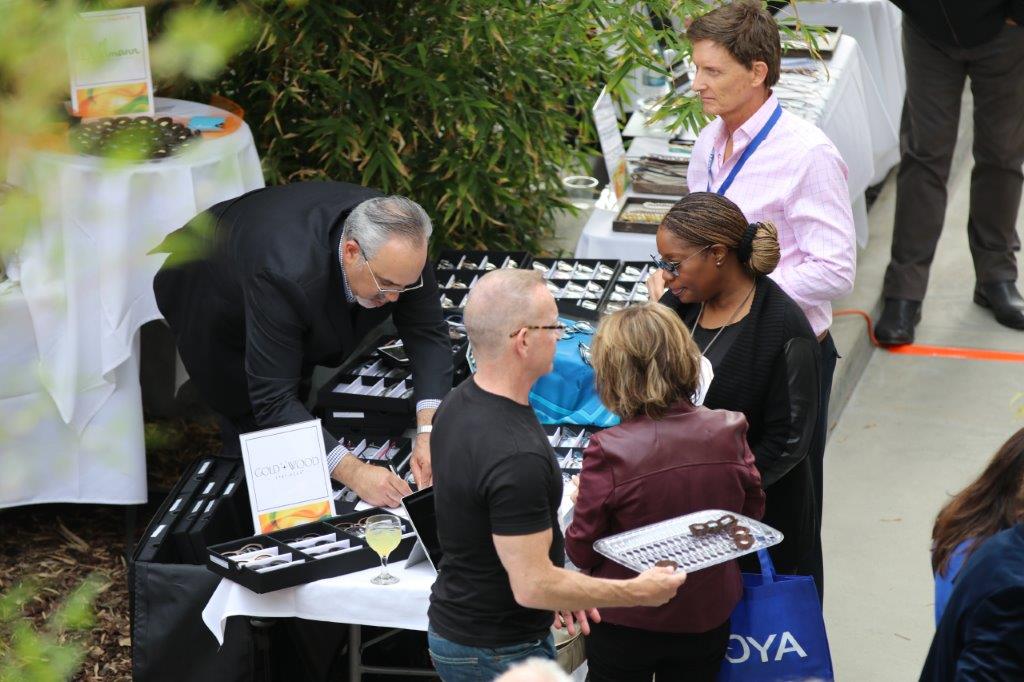 Vendor and shoppers at a table at Raise Your Glasses 2017 Event