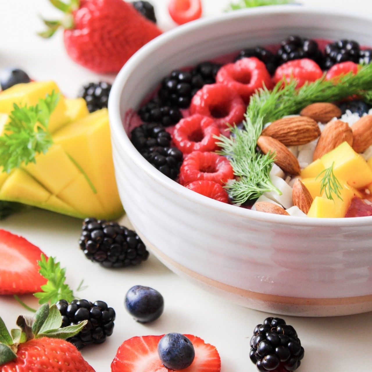 A white bowl filled with berries and nuts on a table