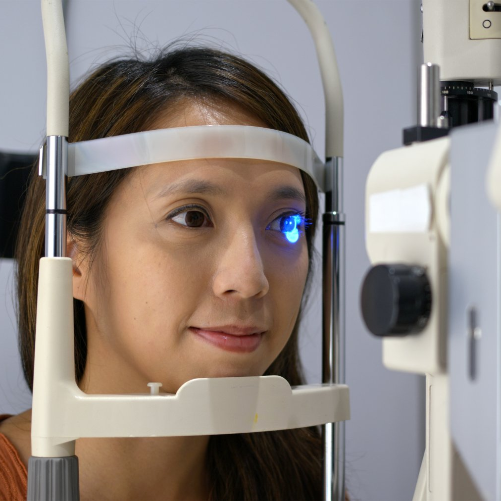 Woman with chin in a piece of diagnostic equipment during an eye exam