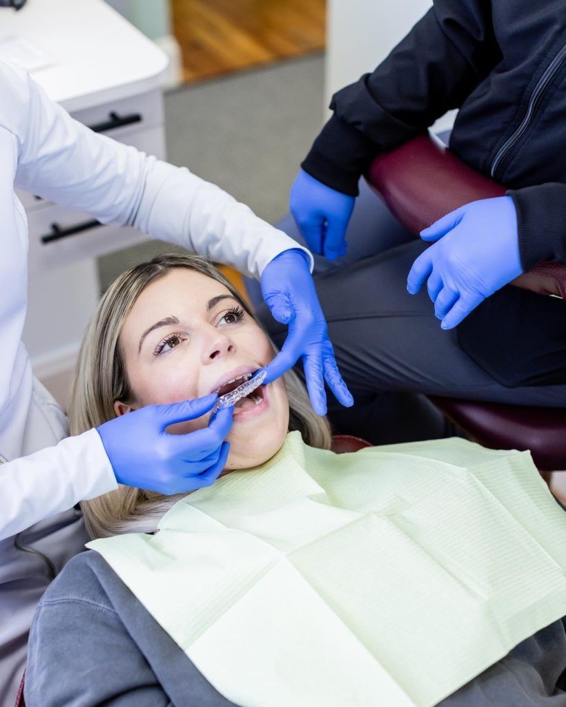 A woman is getting her teeth examined by a dentist in a dental chair.