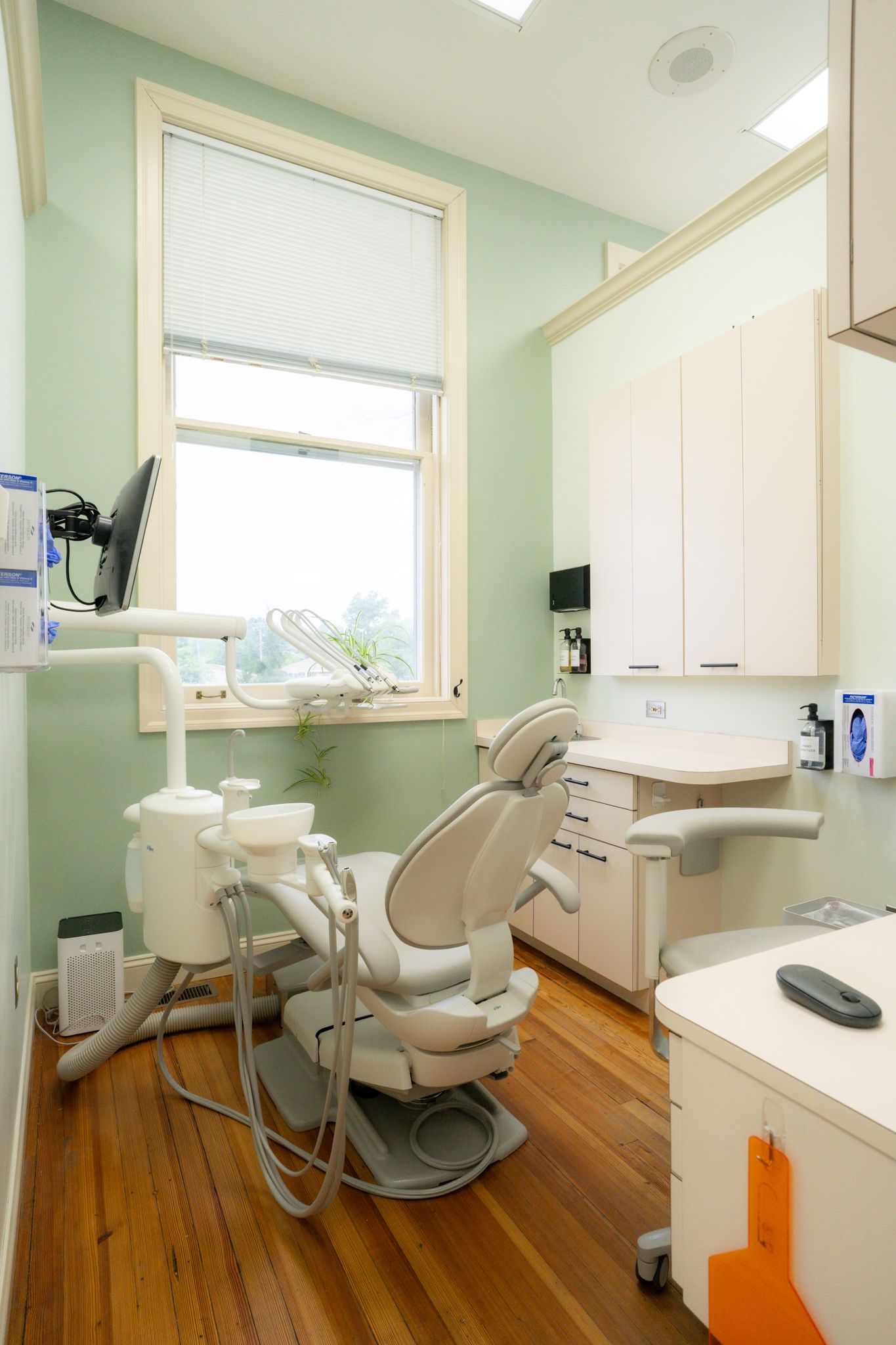 A dental office with a dental chair and a window.