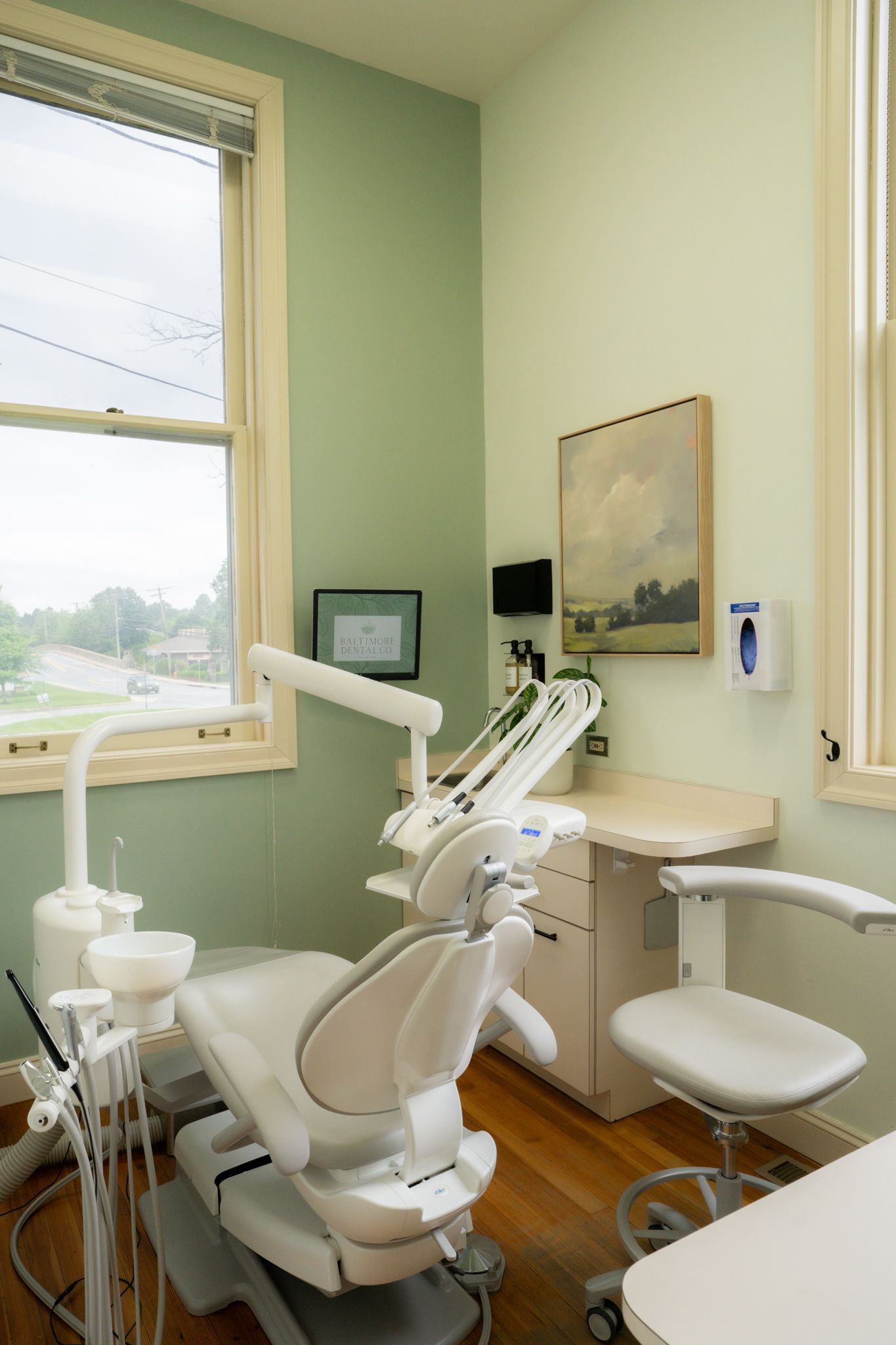 A dental office with a dental chair , desk , and window.