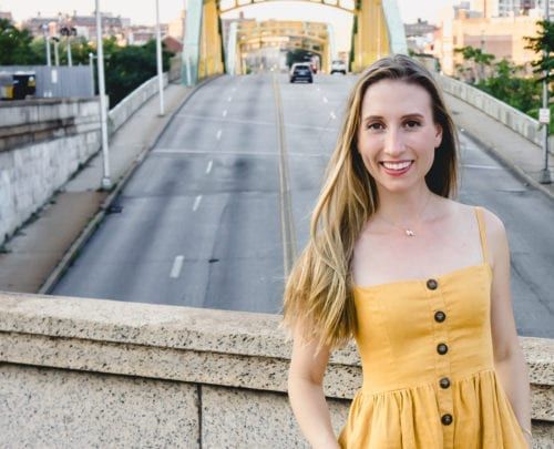 A woman in a yellow dress is standing on a bridge.