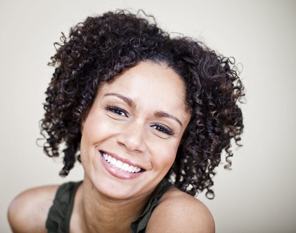 A woman with curly hair is smiling for the camera