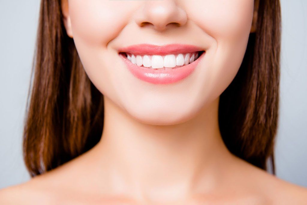 A close up of a woman 's smile with white teeth.
