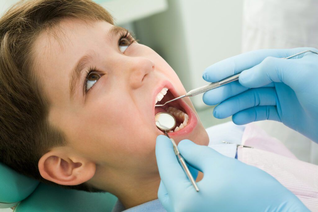 A young boy is getting his teeth examined by a dentist.