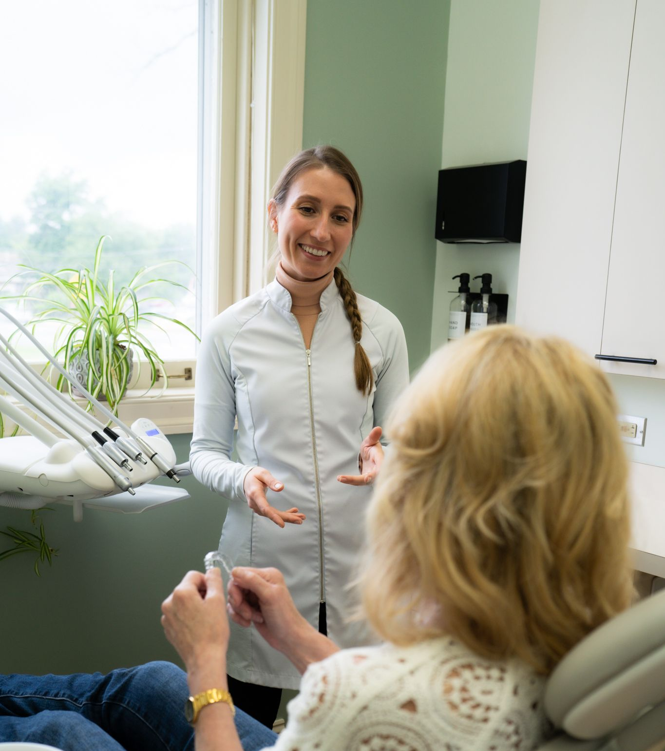 A woman is brushing her teeth in front of a bathroom mirror.