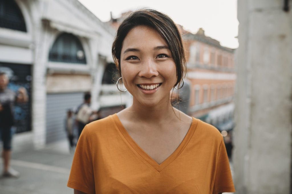 A woman is smiling for the camera while standing on a city street.