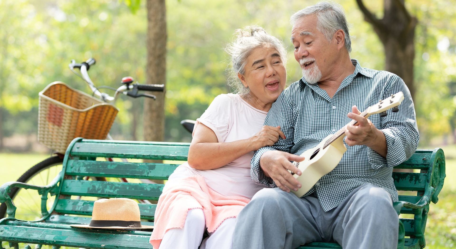 an elderly couple is sitting in the leaves under a tree .