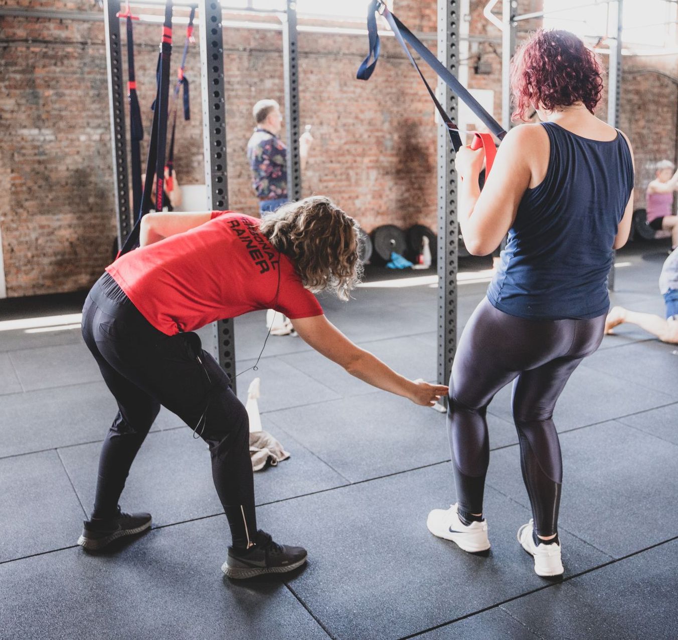 trainer geeft tips tijdens de krachttraining. Persoonlijke fitness begeleiding voor vrouwen.