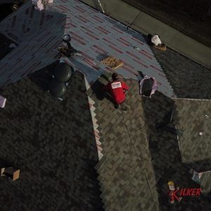 An aerial view of a roof with a man wearing a red shirt that says ' i love you ' on it