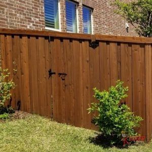 A wooden fence is in front of a brick building.