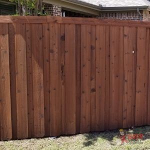 A wooden fence is sitting in the grass in front of a house.