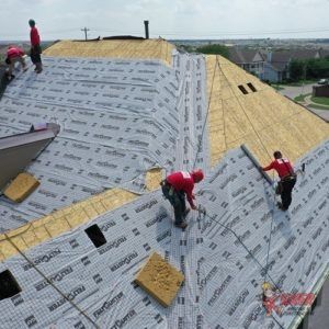 A group of men are working on the roof of a house.