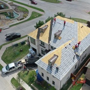 A group of people are working on the roof of a house.