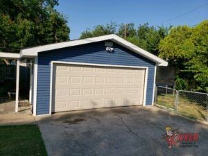 A blue garage with a white door is sitting next to a chain link fence.