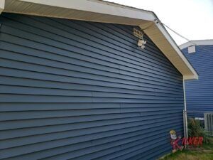 The side of a house with blue siding and a white roof.
