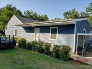 A small house with a blue siding is sitting on top of a lush green lawn.
