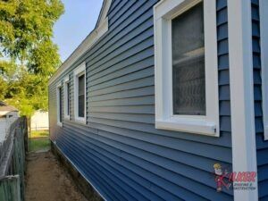 The side of a house with blue siding and white windows.