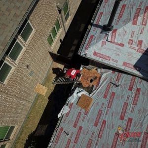 An aerial view of a roof being installed on a brick building.