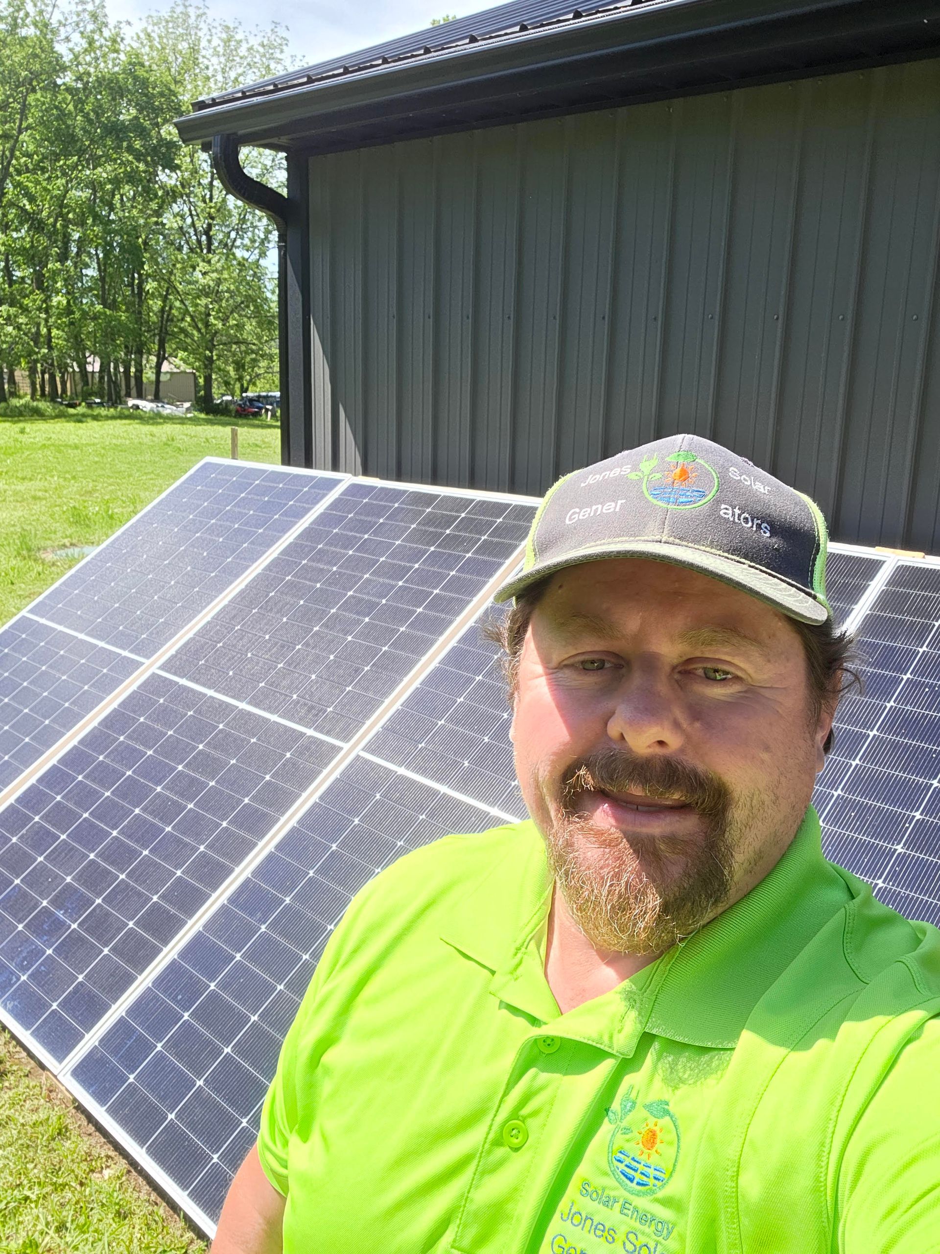 Person in bright green shirt standing beside solar panels in front of a dark building.