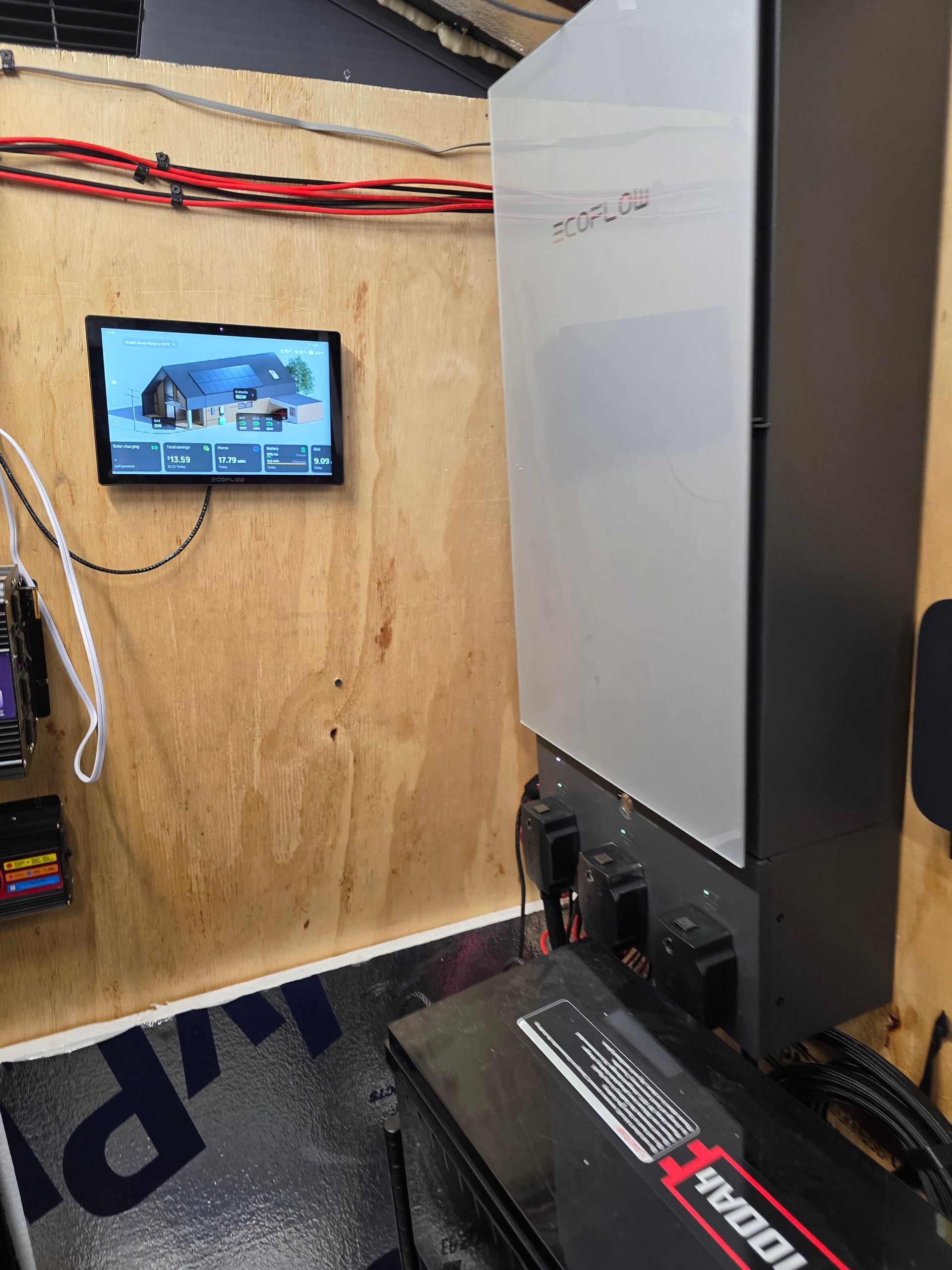 Small room with a wall-mounted screen, cables, and a large machine or cabinet in the foreground.