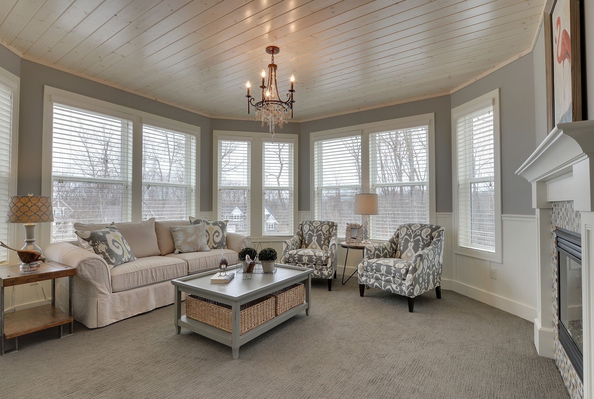 A living room with a wood blinds, couch , chairs , coffee table and fireplace.