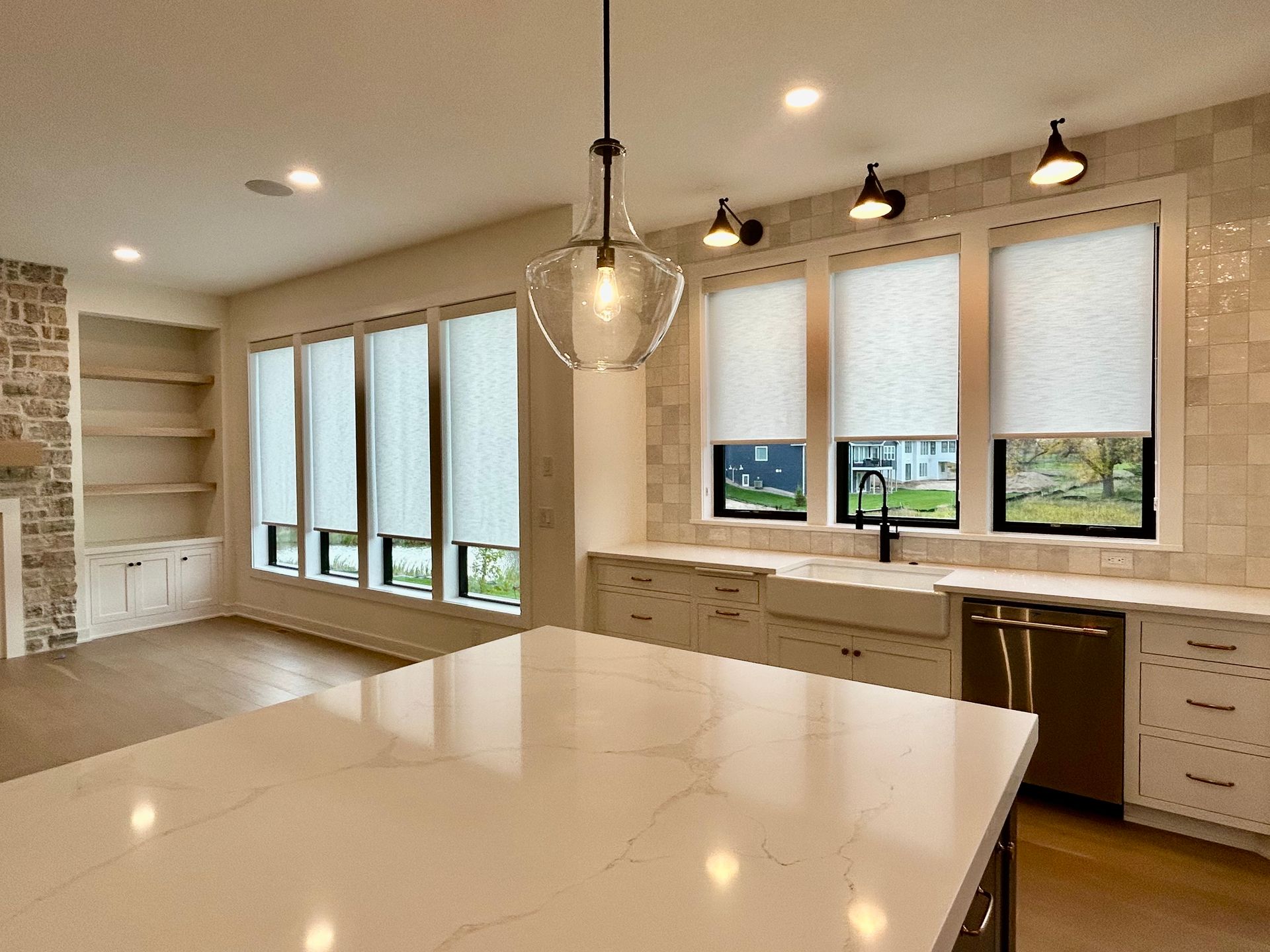 A living room with a dark roller shades, couch , chairs , coffee table and television.