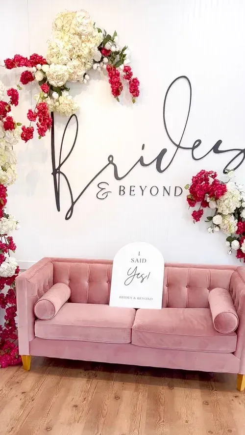 Pink couch with a sign that reads "Mrs. [name]" and a floral backdrop that says "Brides & Beyond."
