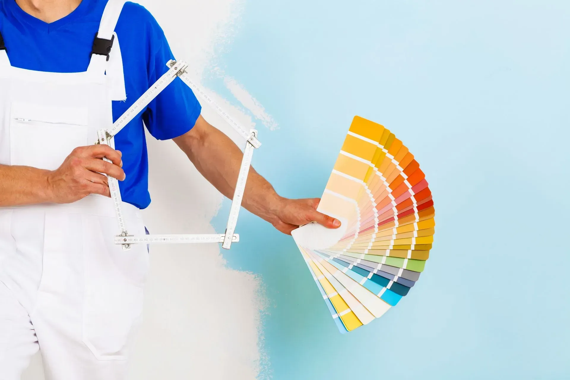 Person holding a fan of color swatches against a light blue wall