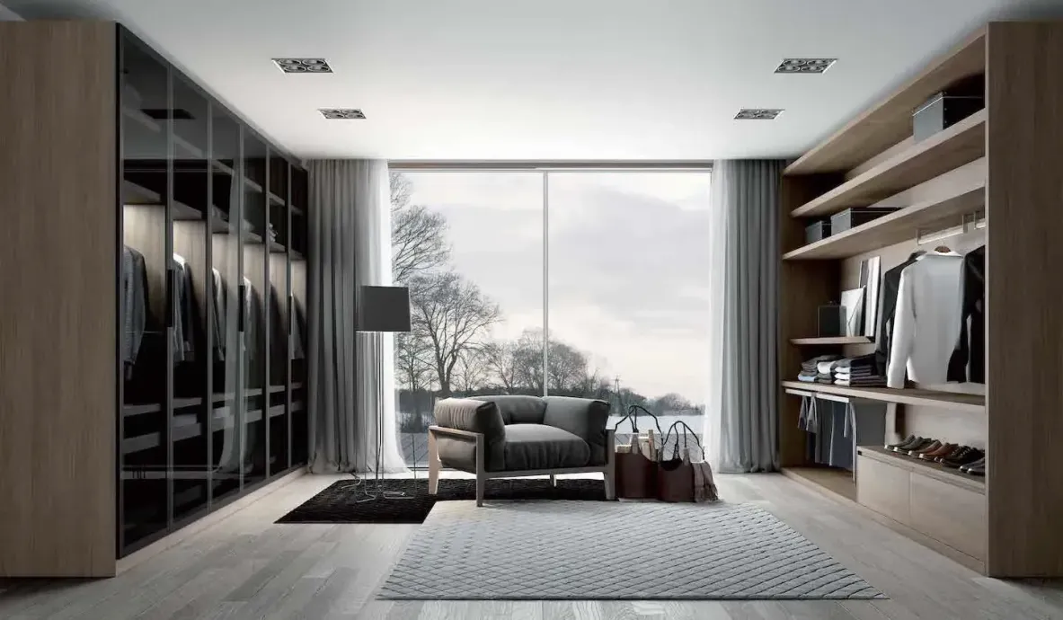 Modern walk-in closet with glass-doored cabinets, a large window, and an armchair.