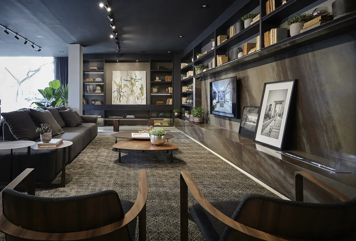 Modern living room with dark gray furniture, bookshelves, and art on walls.