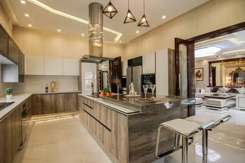 Modern kitchen with wooden island, stainless steel appliances, and marble countertops.