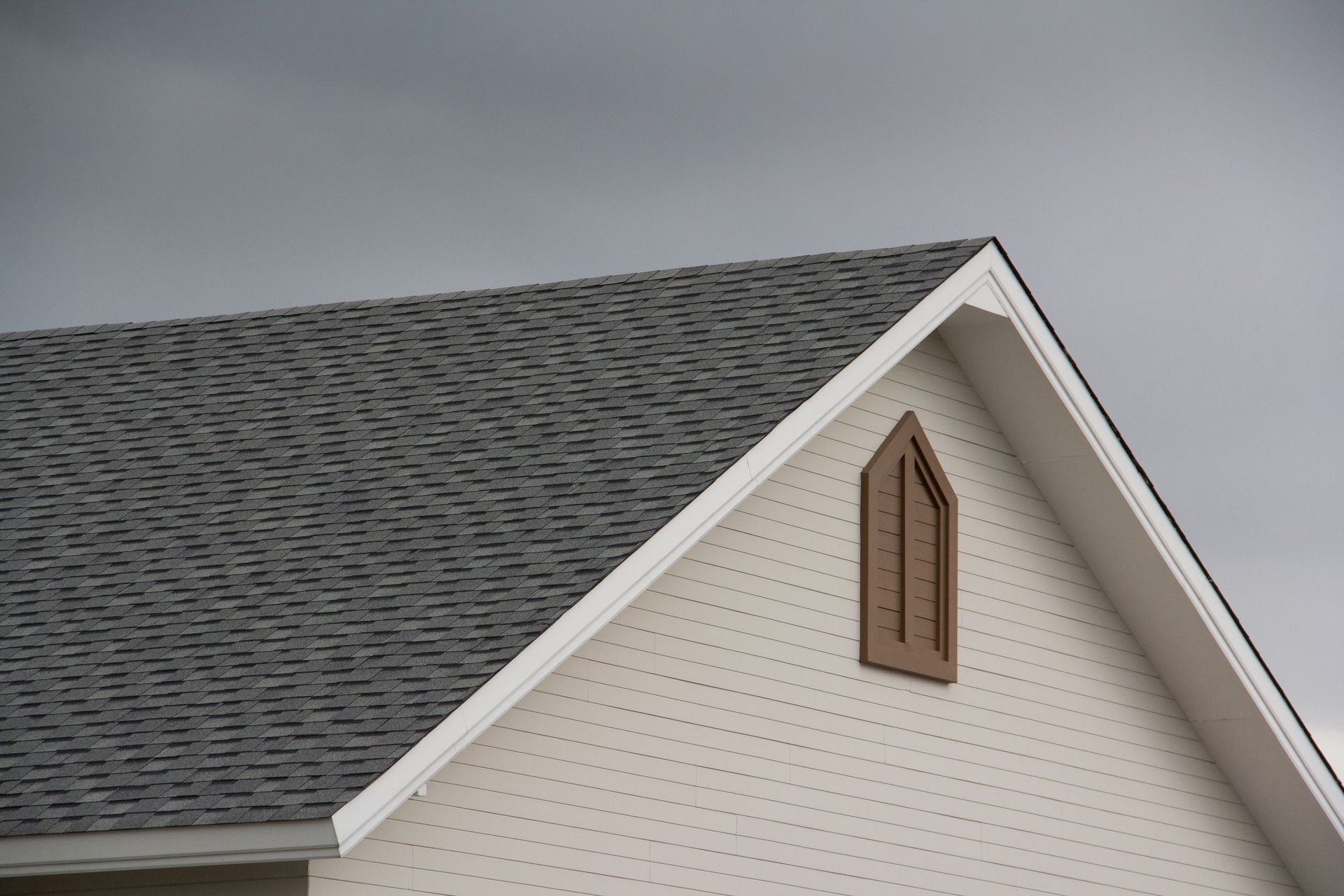 The roof of a house with a window on the side.