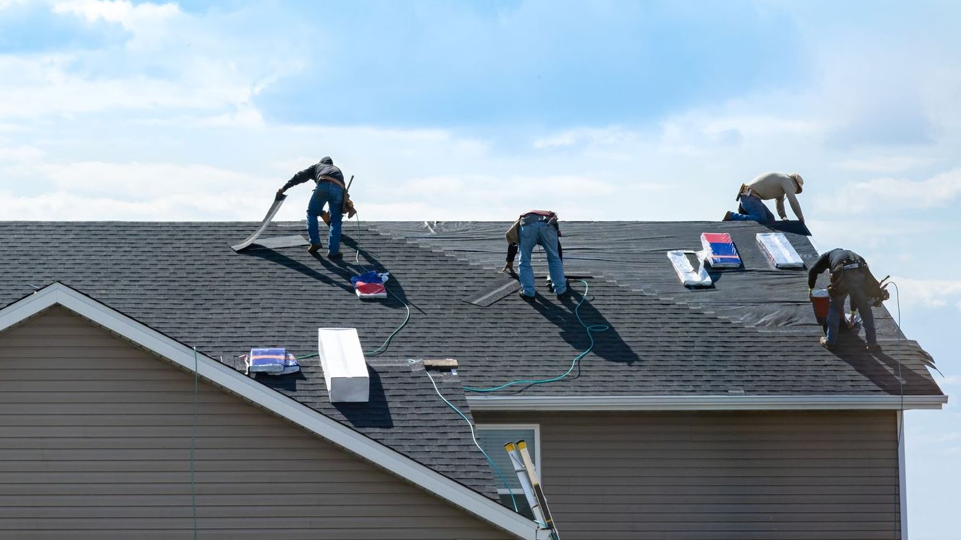 A group of men are working on the roof of a house.