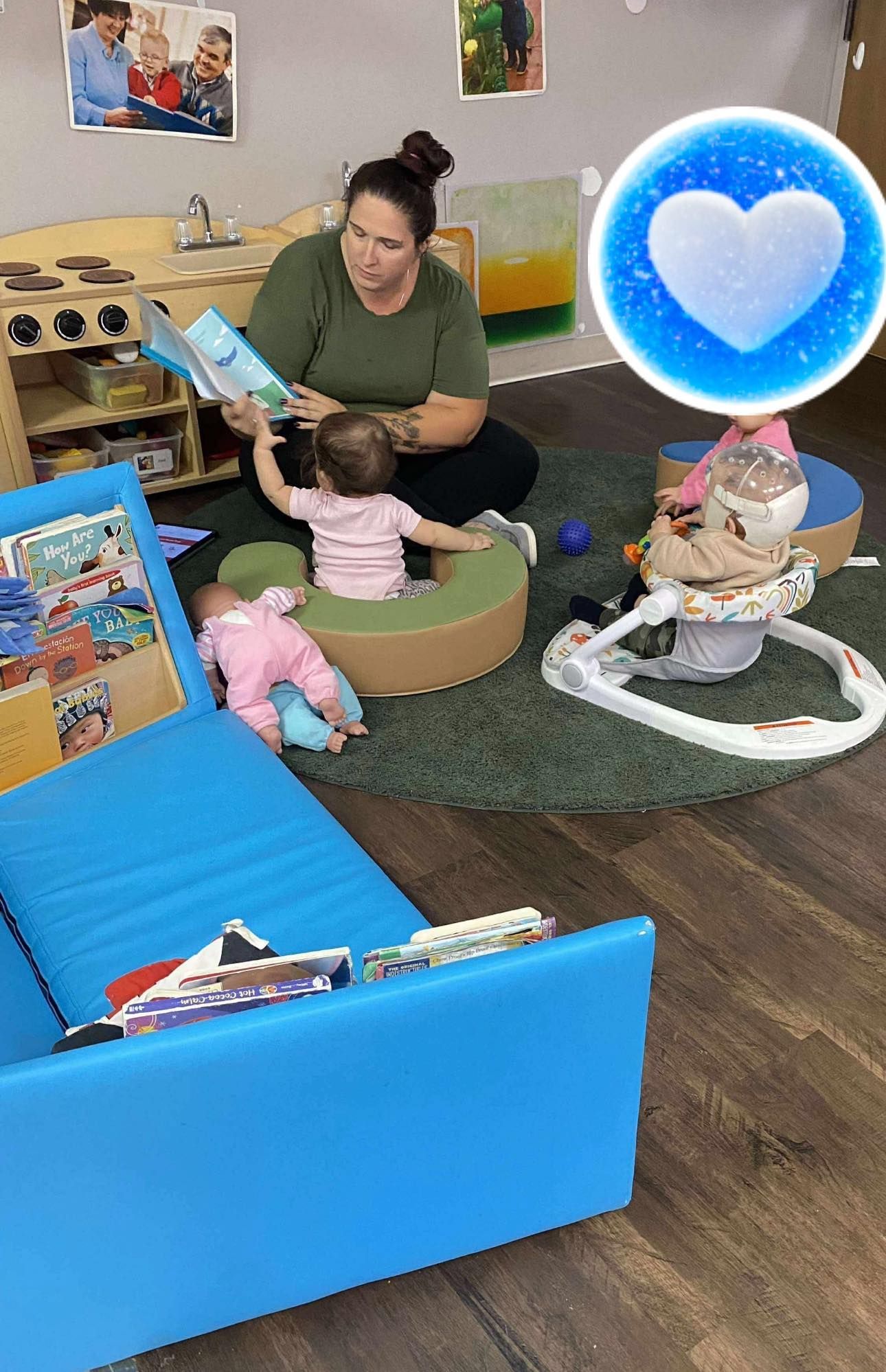 A woman reads a book to two babies on a rug in a playroom.