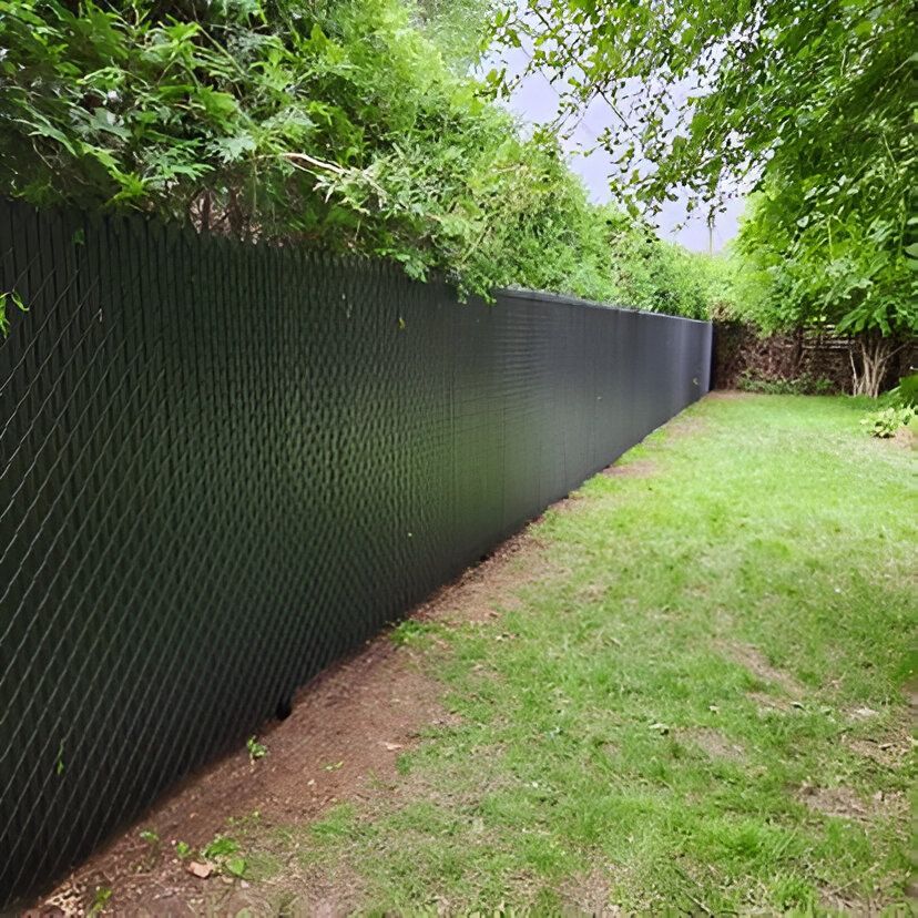 Clôture noire pour préserver l'intimité, bordée de pelouse et de feuillage verts.