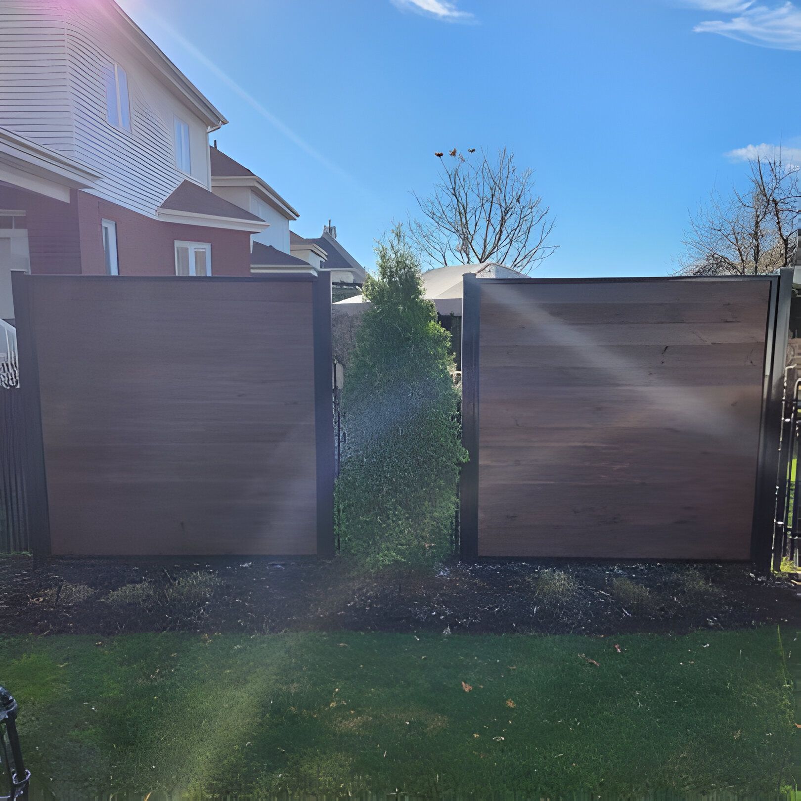Panneaux de clôture en bois pour préserver l'intimité, avec un espace, de l'herbe verte et un ciel bleu.