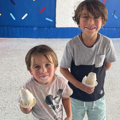 Two young boys standing next to each other holding ice cream cones