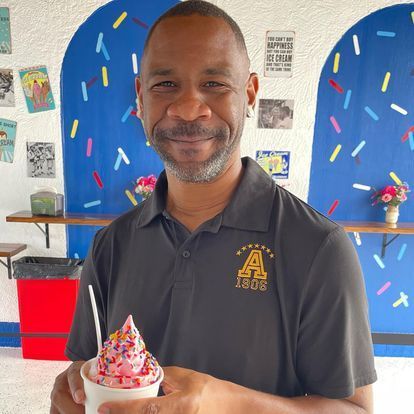 A man in a black shirt is holding a cup of ice cream.