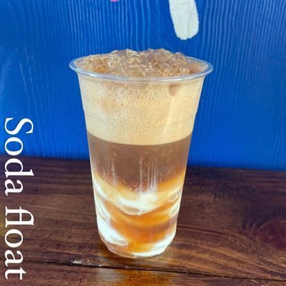 A cup of soda float is sitting on a wooden table.