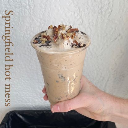 A person is holding a cup of springfield hot mess