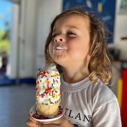 A little girl is eating an ice cream cone with sprinkles.