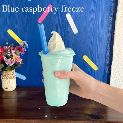 A person is holding a blue raspberry freeze drink