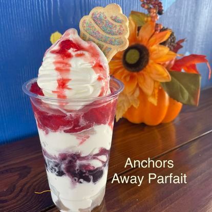 A cup of ice cream with a cookie on top and the words anchors away parfait on the bottom