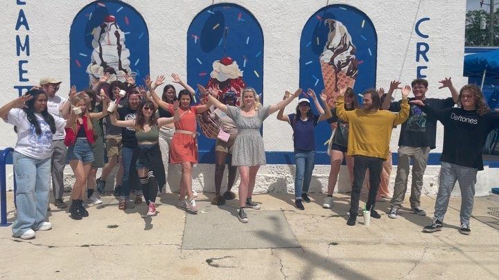 A group of people are posing for a picture in front of an ice cream shop.