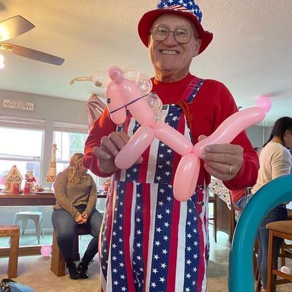 A man in an american flag outfit is holding a pink balloon